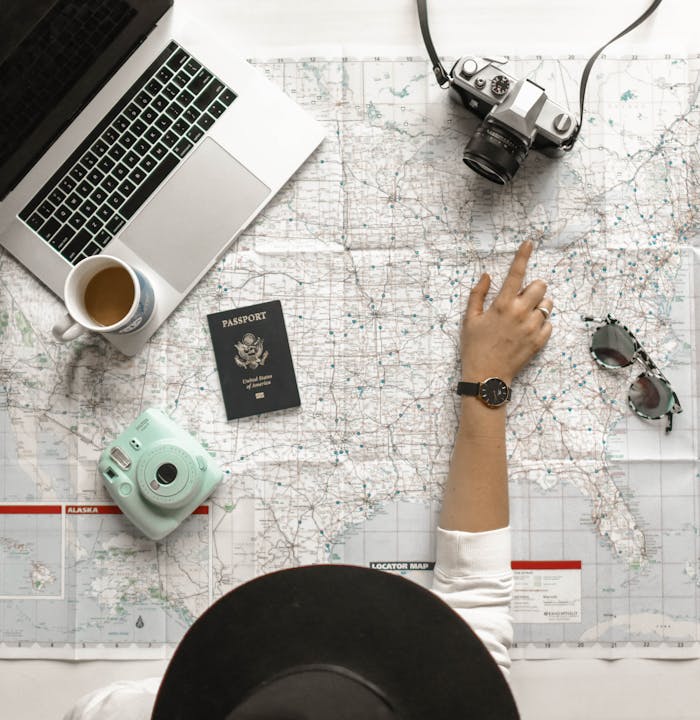 services-04 Hand on map with camera, passport, laptop, and coffee, perfect for travel planning inspiration.
