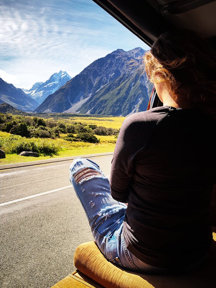 services-03 A woman sits in a van, enjoying the breathtaking view of mountains in Canterbury, New Zealand.