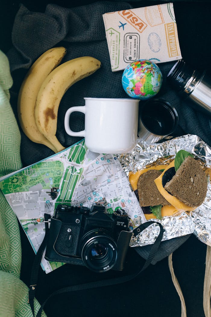 embark Flat lay of travel items including a map, camera, banana, and sandwich, perfect for adventure planning.