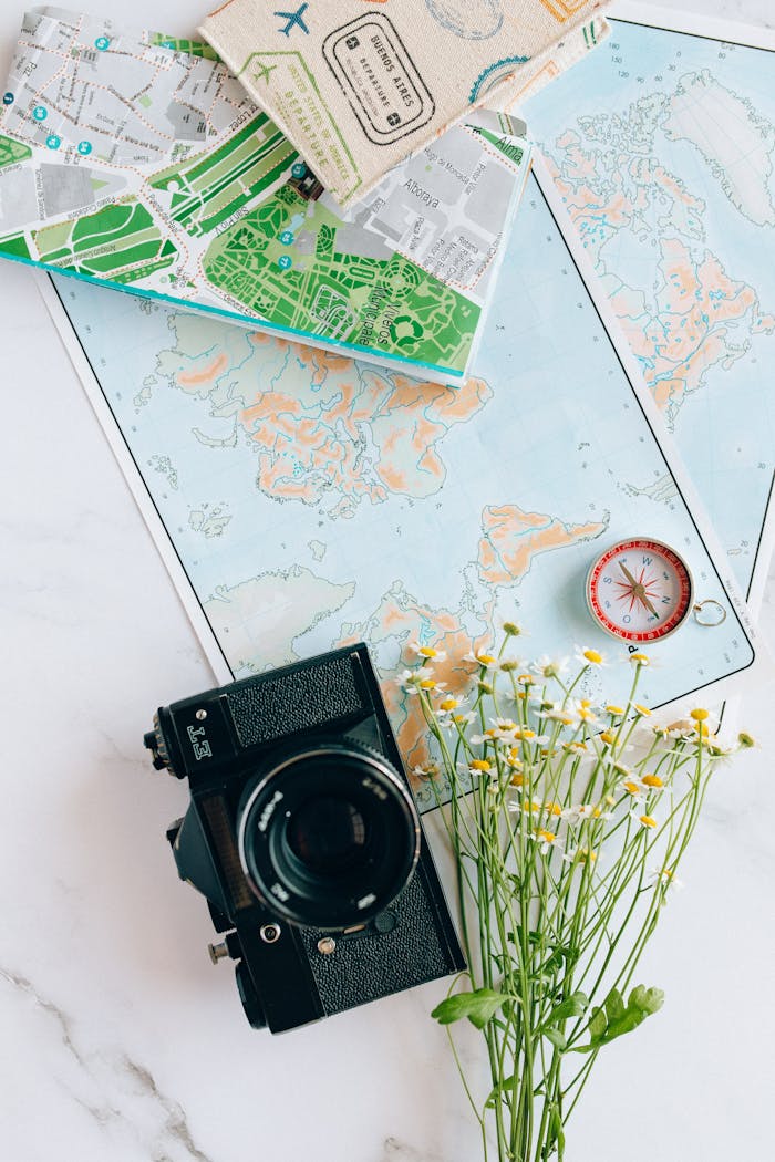 team-02 A nostalgic flatlay of a camera, maps, and compass—perfect for travel enthusiasts.